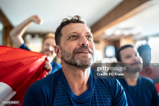 homme d’âge mûr regardant l’équipe de football jouer un match à la maison avec des amis - supporters photos et images de collection