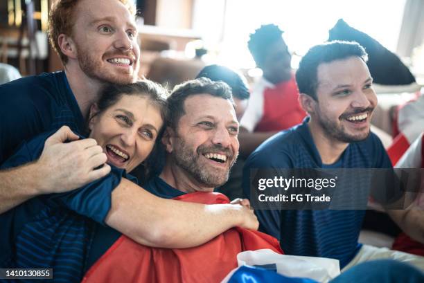 sports fan friends watching a match and celebrating at home - celebrating in sofa stock pictures, royalty-free photos & images