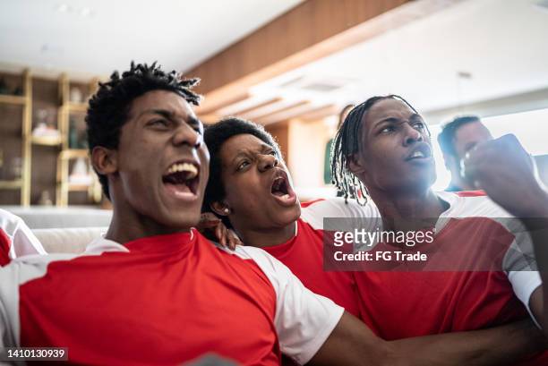 des amis fans de sport regardent un match et célèbrent à la maison - latino media awards photos et images de collection