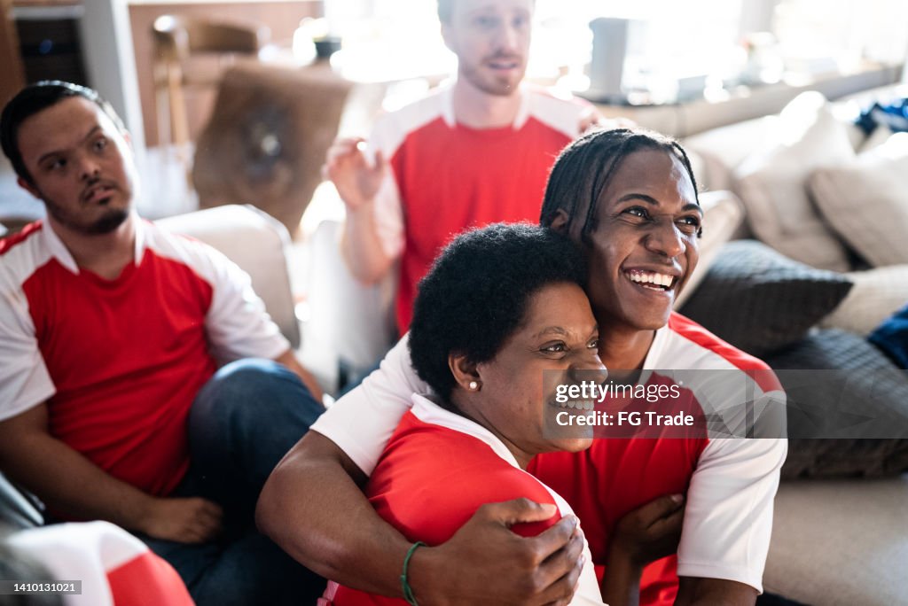 Sports fan friends watching a match and celebrating at home