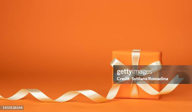 holiday gift box on orange background with copyspace - orange backgrounds stock pictures, royalty-free photos & images