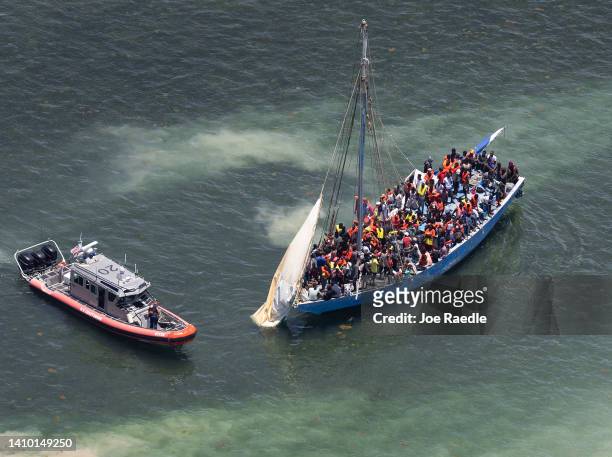 Coast Guard boat sails next to a sailboat containing approximately 150 migrants on July 21, 2022 in Islandia, Florida. U.S. Coast Guard, Miami-Dade...