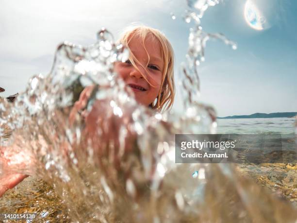 little boy splashing water and smiling - alleen jongens stockfoto's en -beelden