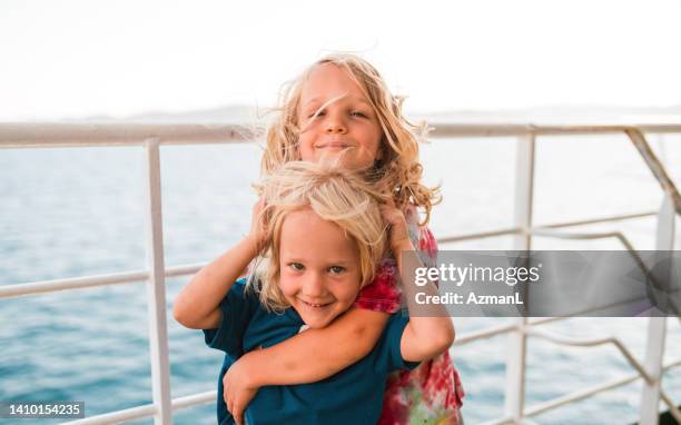 big brother putting arms around small brother while at sea - cruise deck stock pictures, royalty-free photos & images