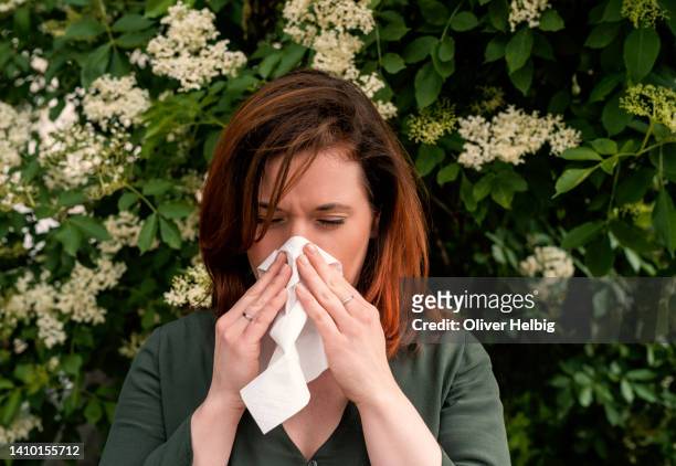 a redhead woman suffers from hay fever and sneezes into a handkerchief - allergia foto e immagini stock