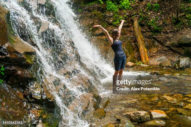 smiling teenage girl enjoying the freedom in the nature, standing with opened arms at the base of glen onoko waterfall, jim thorpe, pa. - jim thorpe pennsylvania stock pictures, royalty-free photos & images
