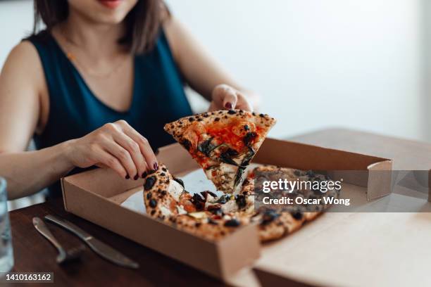 cropped shot of young woman eating pizza from pizza box at. food delivery. takeaway food. - fast food stock pictures, royalty-free photos & images