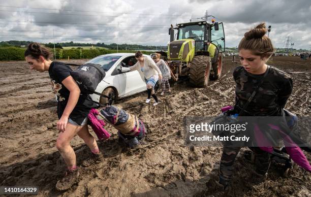 People drag their camping kit through the mud as a car is pushed by a tractor at the 2016 Glastonbury Festival held at Worthy Farm, in Pilton,...