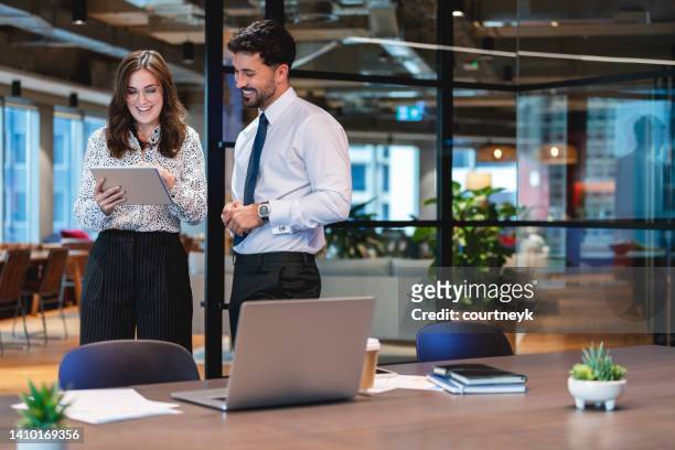 business man and woman standing working together on a digital tablet. - graphics tablet stock pictures, royalty-free photos & images