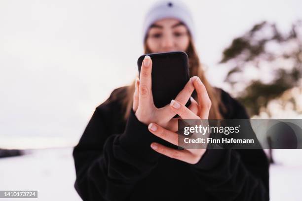 teenager-mädchen, das im winter gute nachrichten auf dem handy im freien liest - digital native stock-fotos und bilder