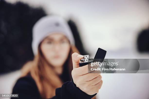 young woman with a cigarette lighter in her hand winter landscape portrait - cigarette lighter stock pictures, royalty-free photos & images
