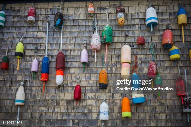 colourful fishing floats against tiled wall - hummerkorb stock-fotos und bilder