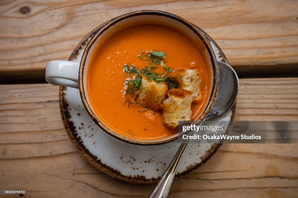 Top down shot of mixed vegetable creamy soup with pieces of toasted pastry. Serving portion of tasty meal in soup bowl.