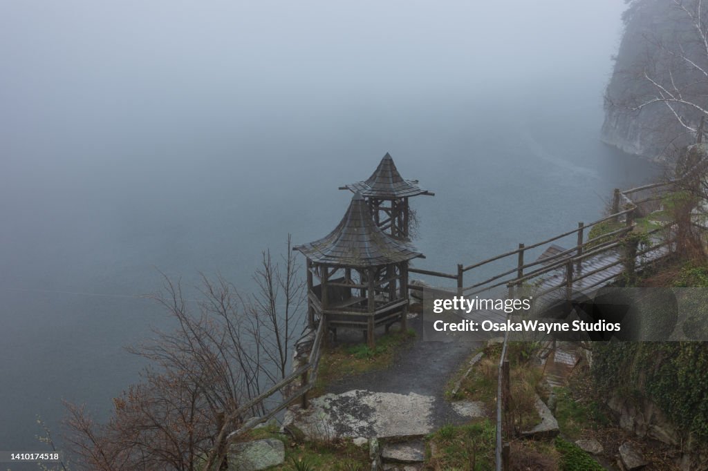 Wooden lookout platform and footbridge, foggy weather at lake