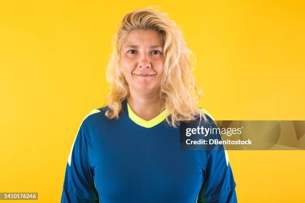 blonde-haired woman dressed as a soccer goalkeeper in a teal blue shirt, on a yellow background. concept of soccer, sport, competition, world cup, qatar and plus size model. - goalkeeper gloves stock pictures, royalty-free photos & images