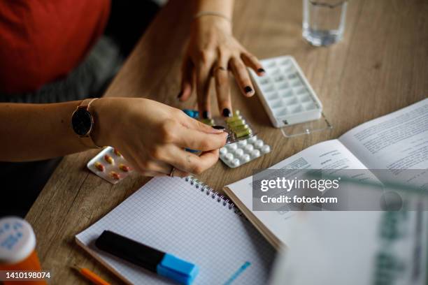 mujer sacando la píldora de su paquete, a punto de organizarla en un organizador de estuches de píldoras - in case of discomfort fotografías e imágenes de stock