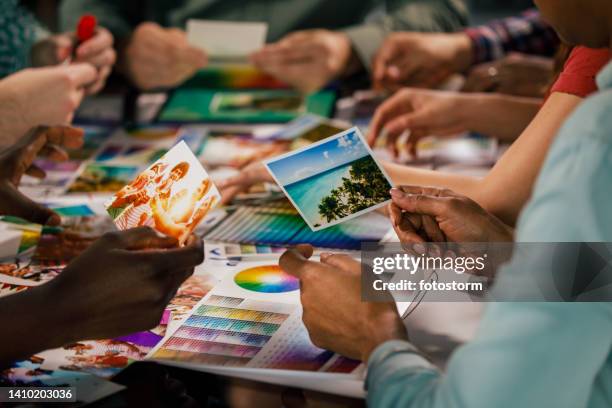 group of design professionals and photographers choosing photographs for a new portfolio - grafisch ontwerpbureau stockfoto's en -beelden