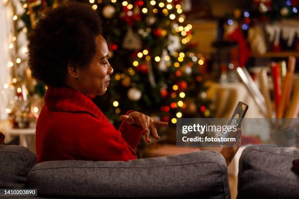 woman video chatting with a friend, wishing her happy christmas holidays - christmas zoom stock pictures, royalty-free photos & images