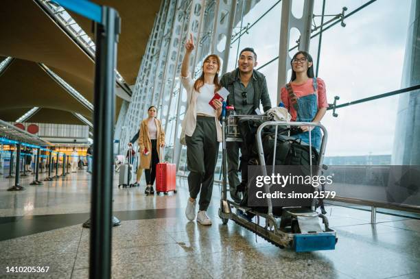 familia asiática con equipaje en tranvía en el aeropuerto - carrito-para-equipaje fotografías e imágenes de stock