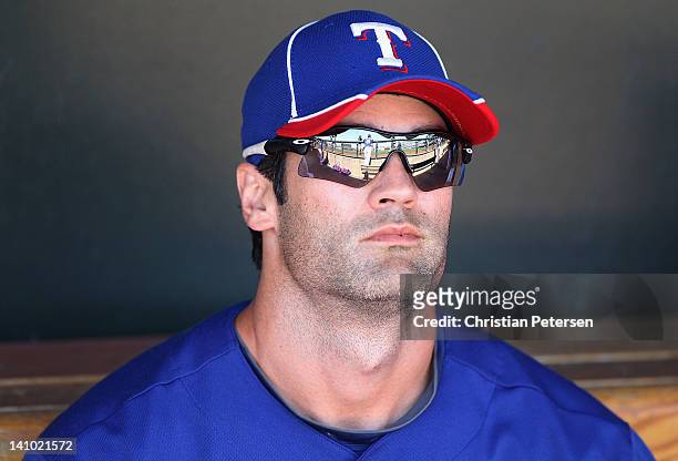 Conor Jackson of the Texas Rangers sits in the dugout during the spring training game against the Los Angeles Dodgers at Surprise Stadium on March 9,...