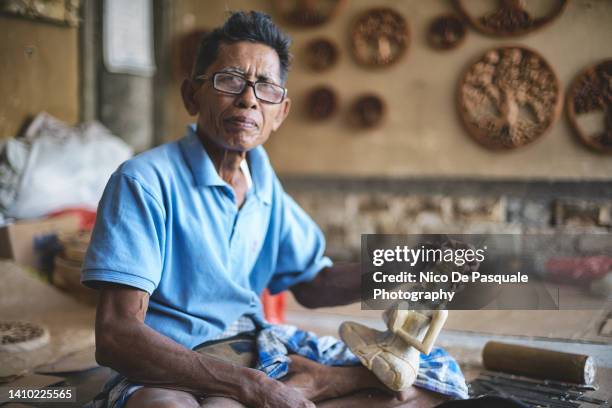 man carving wood in workshop, bali, indonesia - artist portrait stock pictures, royalty-free photos & images