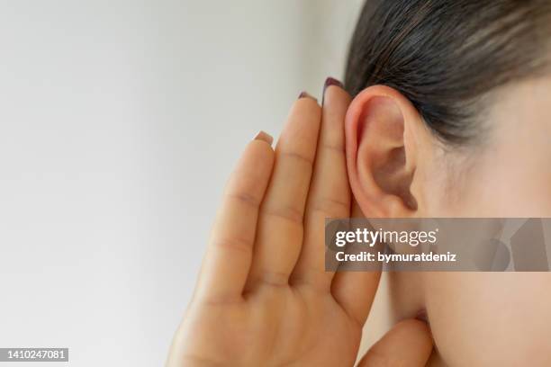 femme avec la main sur l’oreille à l’écoute - woman with cupped hands photos et images de collection