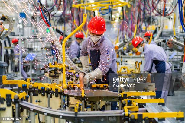 Employees work on the assembly line of Huawei SERES AITO M7 electric SUV at an intelligent factory of SERES Automobile Co., Ltd, a subsidiary of...