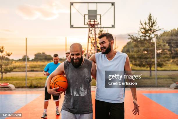 jóvenes abrazados después de un partido de baloncesto - equipo de baloncesto fotografías e imágenes de stock