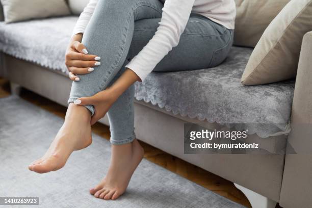 la mujer tiene dolor en la pierna - woman holding legs fotografías e imágenes de stock