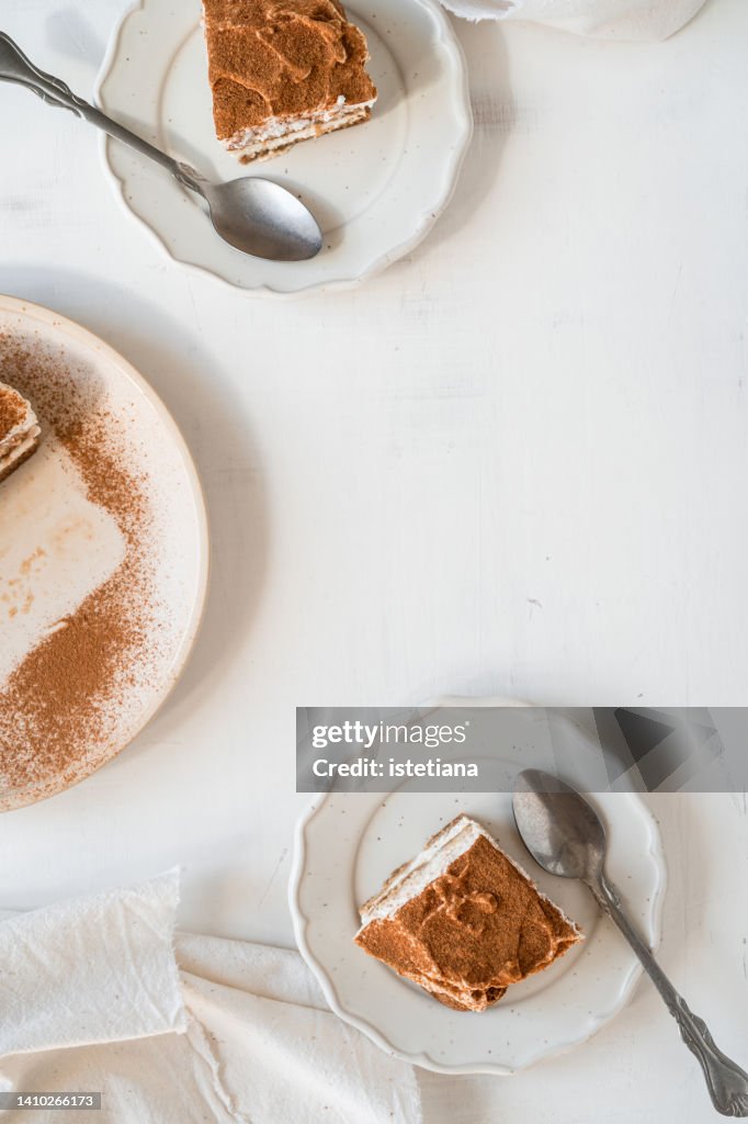 Homemade sliced Tiramisu cake on plates, top view, copy space