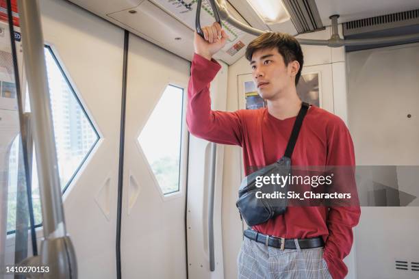 asian businessman passenger man standing inside bts skytrain or mrt underground train at railway platform while traveling to work, bangkok, thailand - mrt train stock pictures, royalty-free photos & images