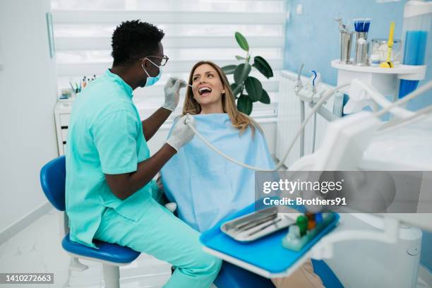 a professional dentist carefully working with his female patient - dentist office stock pictures, royalty-free photos & images