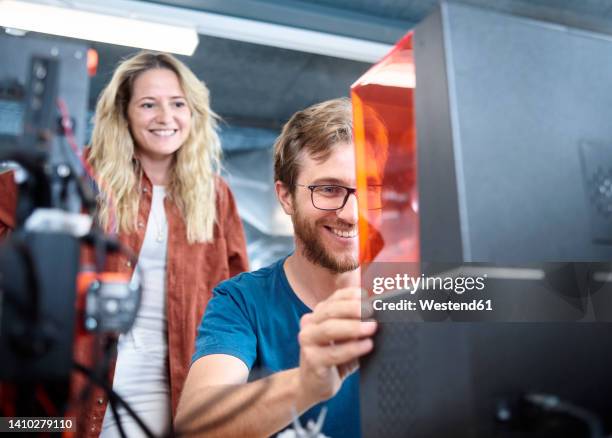 smiling engineer assembling sla printer with colleague at workshop - impression 3d photos et images de collection