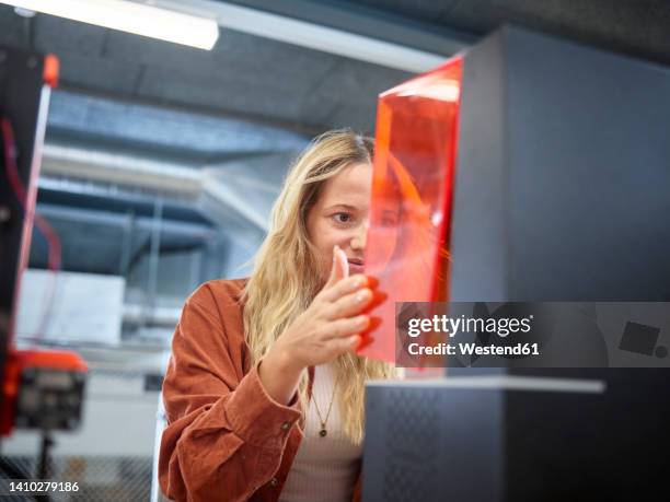 technician opening sla printer at workshop - 3d printer female stock-fotos und bilder