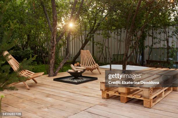 fire place on the wooden veranda next to chairs in garden - pallet industrial equipment stock-fotos und bilder