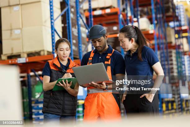 improve warehouse efficiency, employee satisfaction, and engagement. an asian male warehouse engineer has to discuss with his team in front of a shelf rack to determine the warehouse operations process to meet the needs and satisfaction of customers. - service management stockfoto's en -beelden