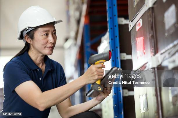 using warehouse barcode scanner technology. side view of an asian female warehouse supervisor uses a barcode reader to scanning on packages for matching the numbers in inventory management software. - rfid technology stock pictures, royalty-free photos & images