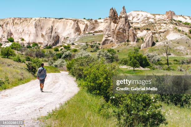 rear view of man walking in a gravel road towards the valley - cappadocia stock pictures, royalty-free photos & images