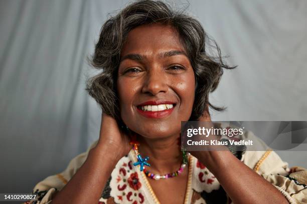 smiling mature woman with hands in hair - indian woman short hair stock pictures, royalty-free photos & images