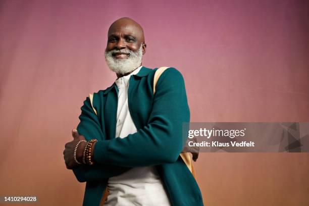 portrait of smiling elderly man with arms crossed - teal portrait stockfoto's en -beelden
