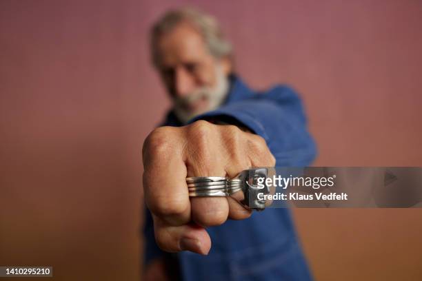 senior man with rings gesturing punch - beards jewellery london stock-fotos und bilder