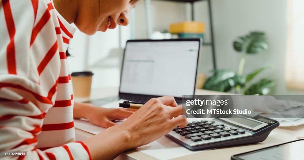 Gros plan Jeune femme asiatique avec pull assis à la réception avec ordinateur portable utiliser calculez aux factures de services publics vérifiez le reçu de carte de crédit facture mensuelle de dépenses à la maison.