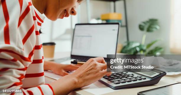 close-up young asian woman with sweater sit front desk with laptop use calculator calculate to utility bills check credit card receipt monthly expense bill at house. - statement stockfoto's en -beelden