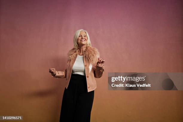 portrait of smiling elderly woman dancing - colour background cool portrait photography joy stock pictures, royalty-free photos & images