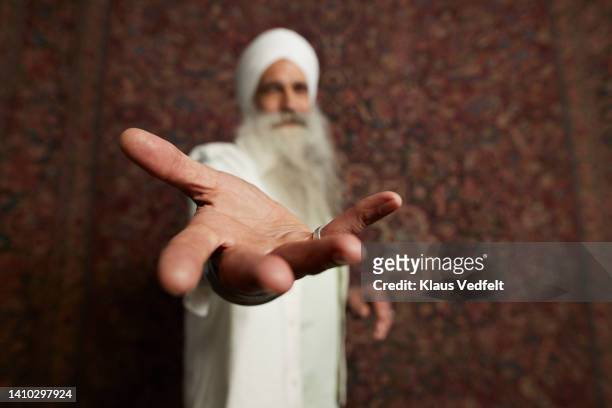 senior man gesturing standing against backdrop - dito umano foto e immagini stock