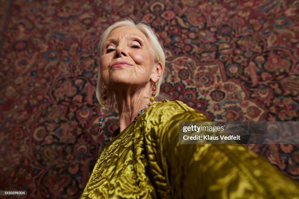 Elderly woman against wall hanging rug