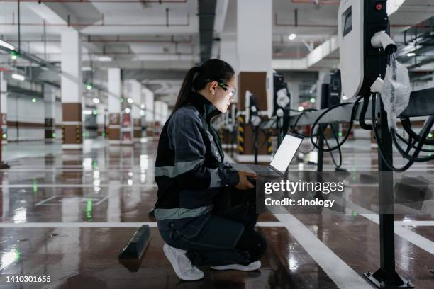 asian female engineer installing charging station in parking lot - automobile industry stock-fotos und bilder