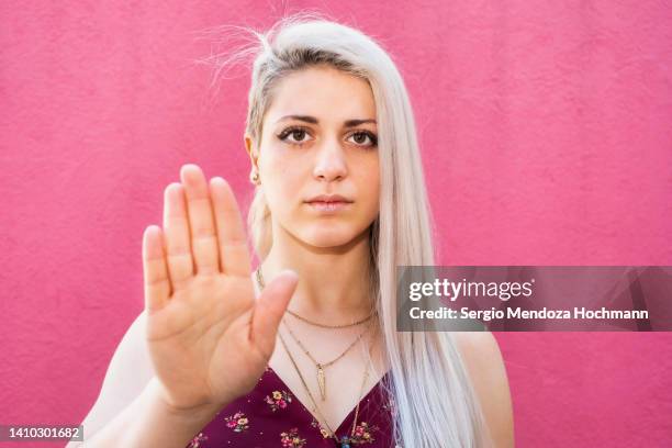 young latino woman looking at the camera and gesturing to stop, platinum blonde hair - hate crimes stock-fotos und bilder