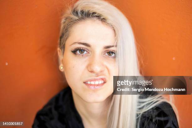 young latino woman looking at the camera sneering, snarling, with platinum blonde hair - cerrando os dentes - fotografias e filmes do acervo