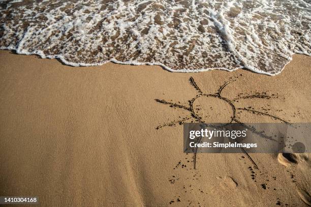 cartoon sun in the sand on the beach by the sea. - sandsun stock-fotos und bilder